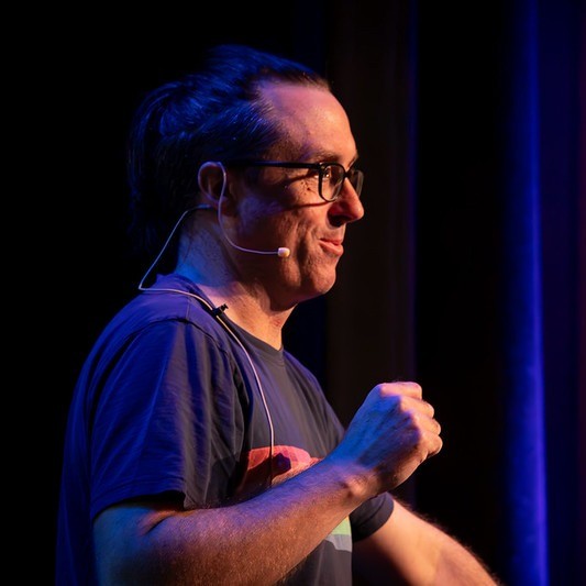 headshot of a man presenting on stage 