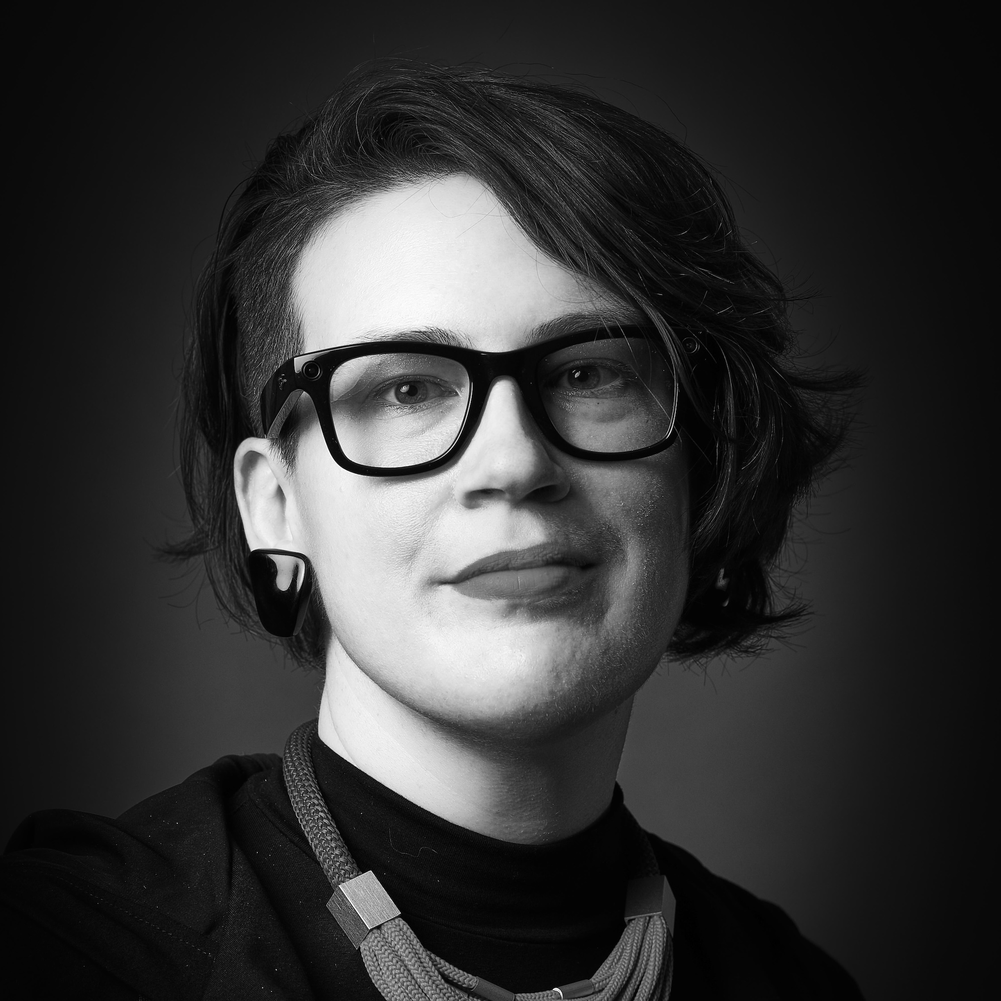 headshot of a young woman wearing glasses and earings and necklace