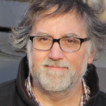 Headshot of a man with grey hair and beard wearing glasses