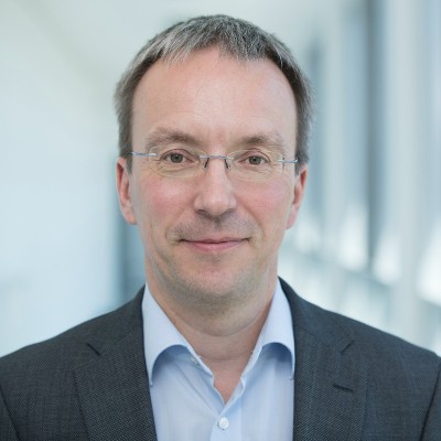 a professor wearing glasses, light blue shirt and grey suit